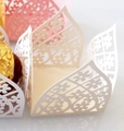 Macro view of laser-cut paper chocolate wrappers with elegant floral hollow patterns - Ivory