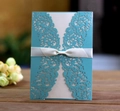 Dettaglio macro dell'invito di nozze traforato al laser con fiocco di raso bianco e blu - Blu Tiffany