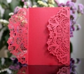 Close-up of red laser-cut wedding invitation with intricate floral lace patterns - Red