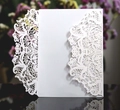 Close-up of laser-cut wedding invitation featuring intricate white lace floral patterns - White