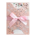 Close-up of laser-cut invitation sleeve with floral watercolor insert and silk ribbon - Pink