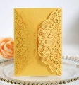 Close-up of golden laser-cut lace invitation with elegant floral patterns on gold cardstock - Gold