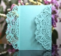 Macro detail of mint green laser-cut wedding invitation with elegant floral lace patterns - Tiffany Blue