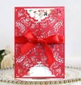 Close-up of laser-cut red wedding invitation with silk bow on decorative plate - Pearlescent Red