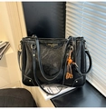 Dettaglio borsa tote nera lucida con logo in metallo, ciondolo di perline e borchie di base - Nero con ciondolo