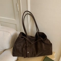 Détail d'un sac cabas marron foncé en daim avec sa pochette assortie sur un canapé - Marron