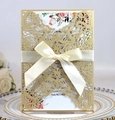 Detail of laser-cut wedding invitation with gold sleeve and white satin ribbon bow - Beige Gold