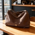 Sac fourre-tout vintage en daim marron foncé avec boucle dorée sur table en bois - Marron