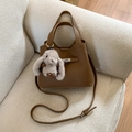Detail of brown lychee grain leather handbag with metal clasp and plush rabbit charm - Brown (With Pendant)
