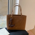 Brown suede tote bag with dachshund charm and gold logo on a cozy autumn backdrop - Brown with Pendant