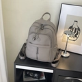 Grauer Rucksack aus genarbtem Leder mit Metallkette auf einem schwarzen Regal - Grau