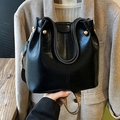Bolso saco negro brillante con correa tejida geométrica y detalles de remaches dorados - Negro