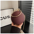 Detailansicht einer matten burgunderroten Kugel-Abendtasche mit goldenem Ringgriff und Kette - Braun