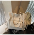 Detail of white quilted tote bag featuring glossy finish and elegant gold chain strap - White