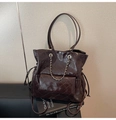 Detail of dark chocolate quilted tote with gold chain accent and glossy finish - Brown