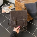 Macro detail of dark brown vintage PU leather texture and decorative buckles on a backpack - Brown