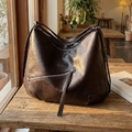 Grande borsa hobo vintage in ecopelle marrone con dettaglio zip su tavolo in legno - Marrone