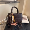Borsa a mano marrone scuro coccodrillo con dettagli dorati e ciondolo su mobile bianco - Con Ciondolo / caffè