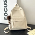 Detail view of cream faux leather backpack with textured finish and brown pompom charm - With Charm / White