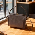 Vintage dark brown box-style leather handbag with golden lock on a wooden cafe table - Brown