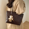 Bolso tote acolchado marrón oscuro con cadena y colgante de oso mostrado en modelo - Color Café (Con Colgante)