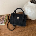 Detail view of black vintage crossbody bag with silver twist lock on wooden surface - Black