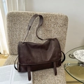 Detailed view of deep brown vintage leather messenger bag on a cozy fabric chair - Cocoa Brown