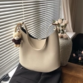 Elegante borsa hobo in pelle crema con ciondolo a orsetto su sfondo di abito nero - Con Ciondolo / Bianco Sporco