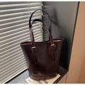 Close-up of deep brown glossy leather tote bag with elegant golden metallic buckle - Coffee