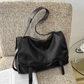 Retro black leather messenger bag with flap closure and adjustable strap on a chair - Black