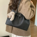 Schwarze Leder-Shopper-Tasche mit Silberverschluss und Plüsch-Hasen-Anhänger am Model - Schwarz mit Anhänger