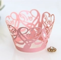 Macro shot of laser-cut pink cupcake wrapper with elegant Love and heart patterns - Pink