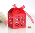 Close-up of red laser-cut wedding favor box with pearl paper texture and silk ribbon bow - Pearlescent Red