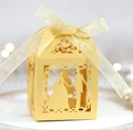 Close-up of laser-cut wedding favor box with bride and groom silhouette and gold ribbon - Gold