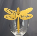 Close-up of golden dragonfly laser-cut place card with glitter finish on a wine glass rim - Gold