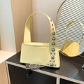 Pale yellow leather underarm bag with silver rivet studs on black cabinet display - Yellow