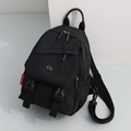 Detail view of black nylon backpack with durable zipper pockets and metal logo badge - Large / Black