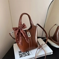 Brown leather bucket bag with polka dot scarf and silver lock on vintage books - Brown