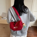 Sac bandoulière rouge en nylon type dumpling avec pendentif porté par un mannequin - Avec Pendentif / Bordeaux