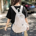 Zaino casual in nylon beige minimalista mostrato sul retro da una modella in città - Bianco Sporco