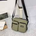 Olive green nylon crossbody bag with dual zipper pockets on a grey felt surface - Green