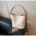 Detail van een crèmekleurige lederen bucket bag met bloemenprint en metalen bedels - Off-wit
