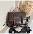 Detail of dark brown retro leather shoulder bag with buckle straps and brand lettering - Brown