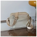 Detalle de bolso bandolera de nailon beige con tres cremalleras sobre mesa - Talla única / Caqui