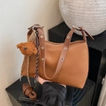 Minimalist caramel brown shoulder bag with metal eyelet straps and plush bear charm - With Charm / Brown