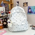White backpack with black floral patterns and plush rabbit pendant on a desk - With Charm / White
