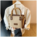 Detail of woven straw bag with bamboo handle and leather trim on white blazer - Khaki