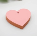 Vista macro di etichette in legno di tiglio rosa a forma di cuore con fori per appenderle - Rosa