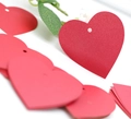 Macro-opname van rode hartvormige cadeaulabels met gaten voor bruiloft decoratie en DIY - Rood