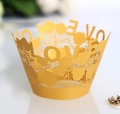 Macro detail of laser-cut gold lace cupcake wrapper featuring decorative LOVE lettering - Gold